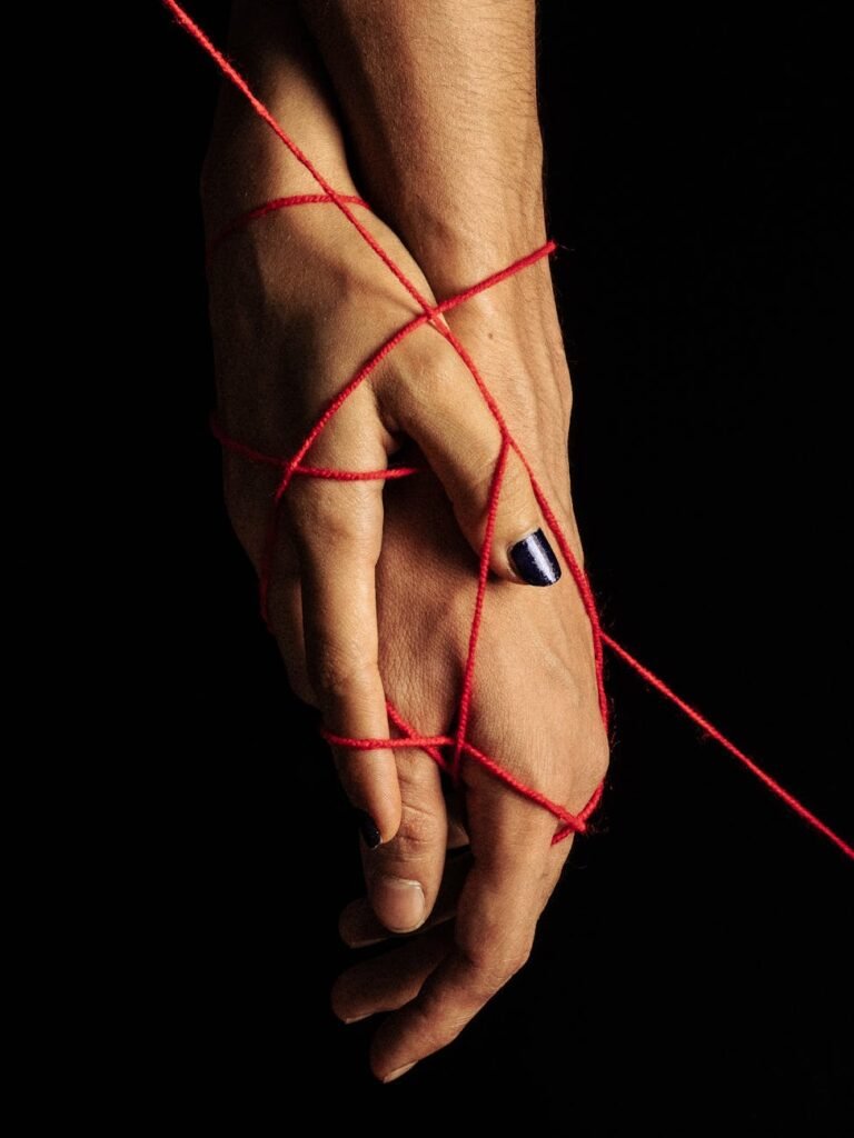 conceptual portrait of hands with red thread